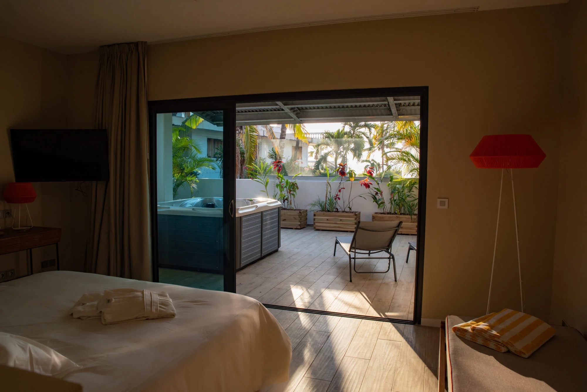 Vue intérieure de la Chambre Tropicale ouvrant sur la terrasse et le jacuzzi privatif