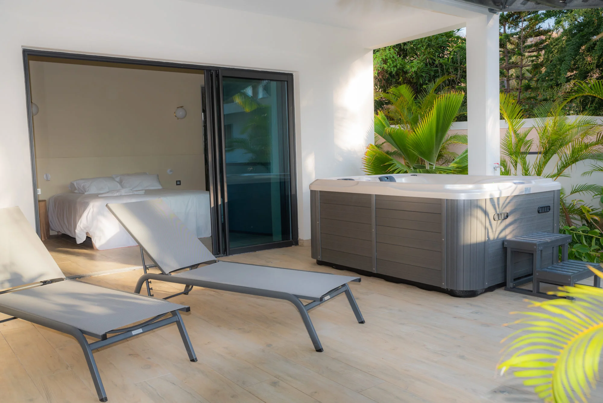 Terrasse privée avec jacuzzi et transats de la Chambre Tropicale